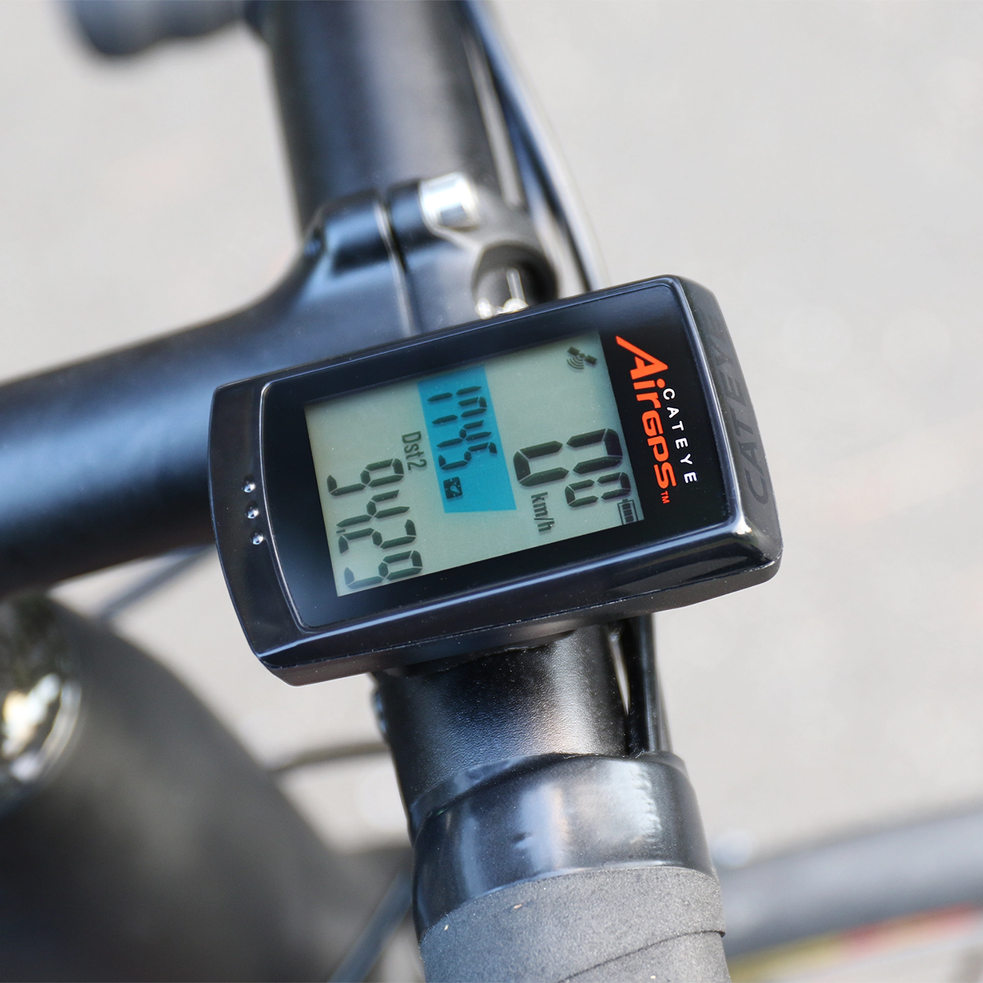 A close-up of the CATEYE AirGPS bike computer on a handlebar, showing distance, speed, and time with enhanced GPS accuracy via the CatEye Cycling app.