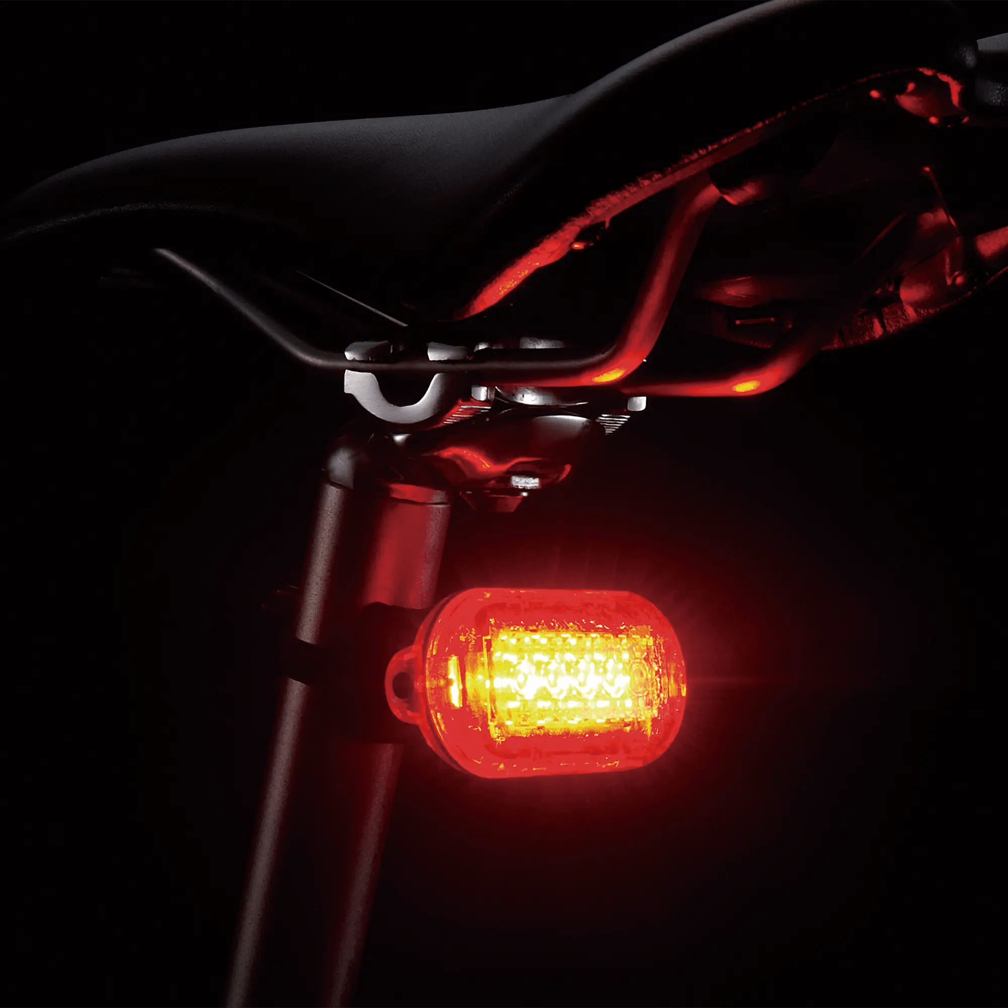 The CATEYE Hl-El160 & OMNI 5 cycling light set is mounted to the seat post under a black saddle, glowing brightly in the dark to ensure 360° visibility.