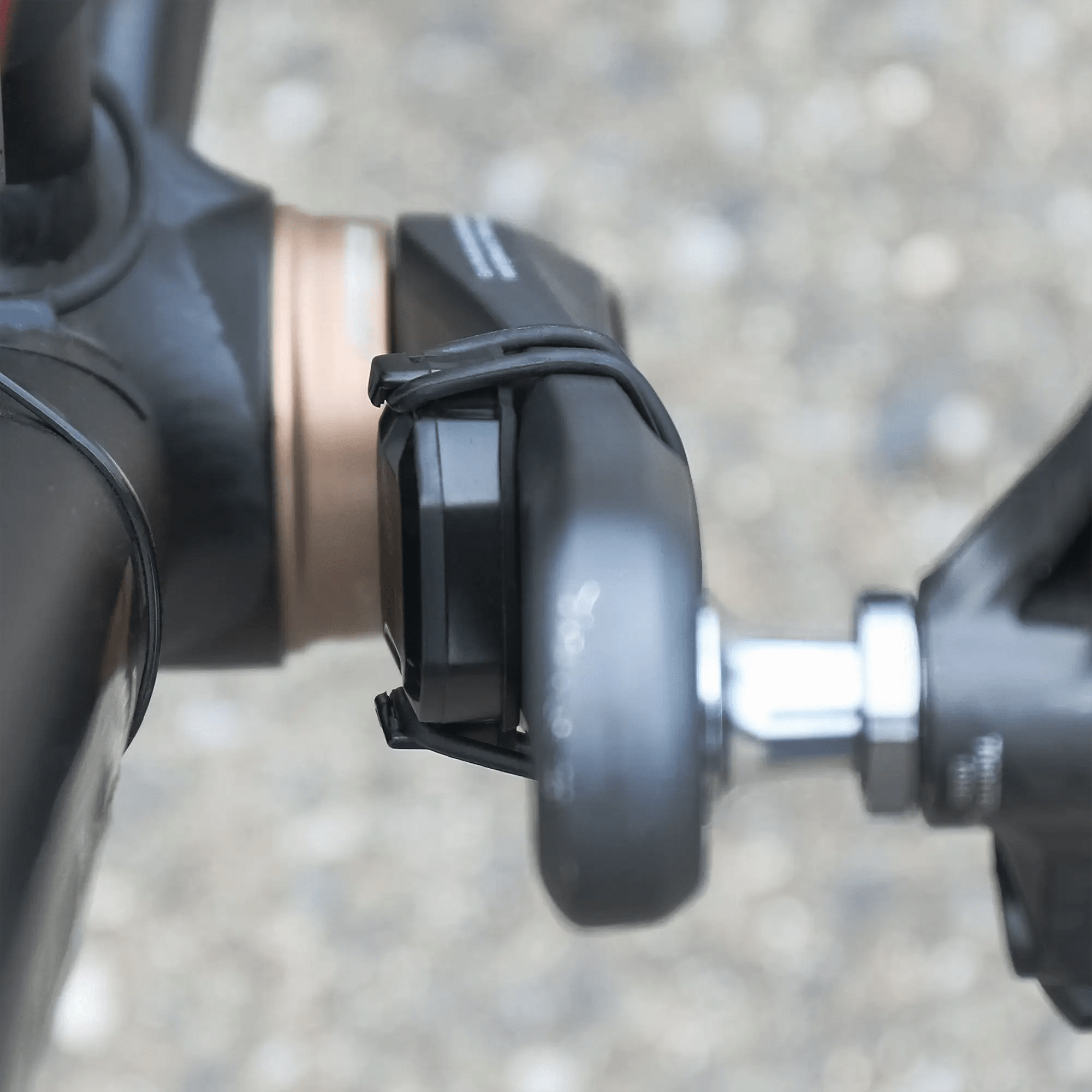 Close-up of a bicycle crank arm with a pedal, showing the CATEYE AirGPS sensor secured near the spindle. The blurred background highlights how AirGPS enhances GPS accuracy for cyclists.