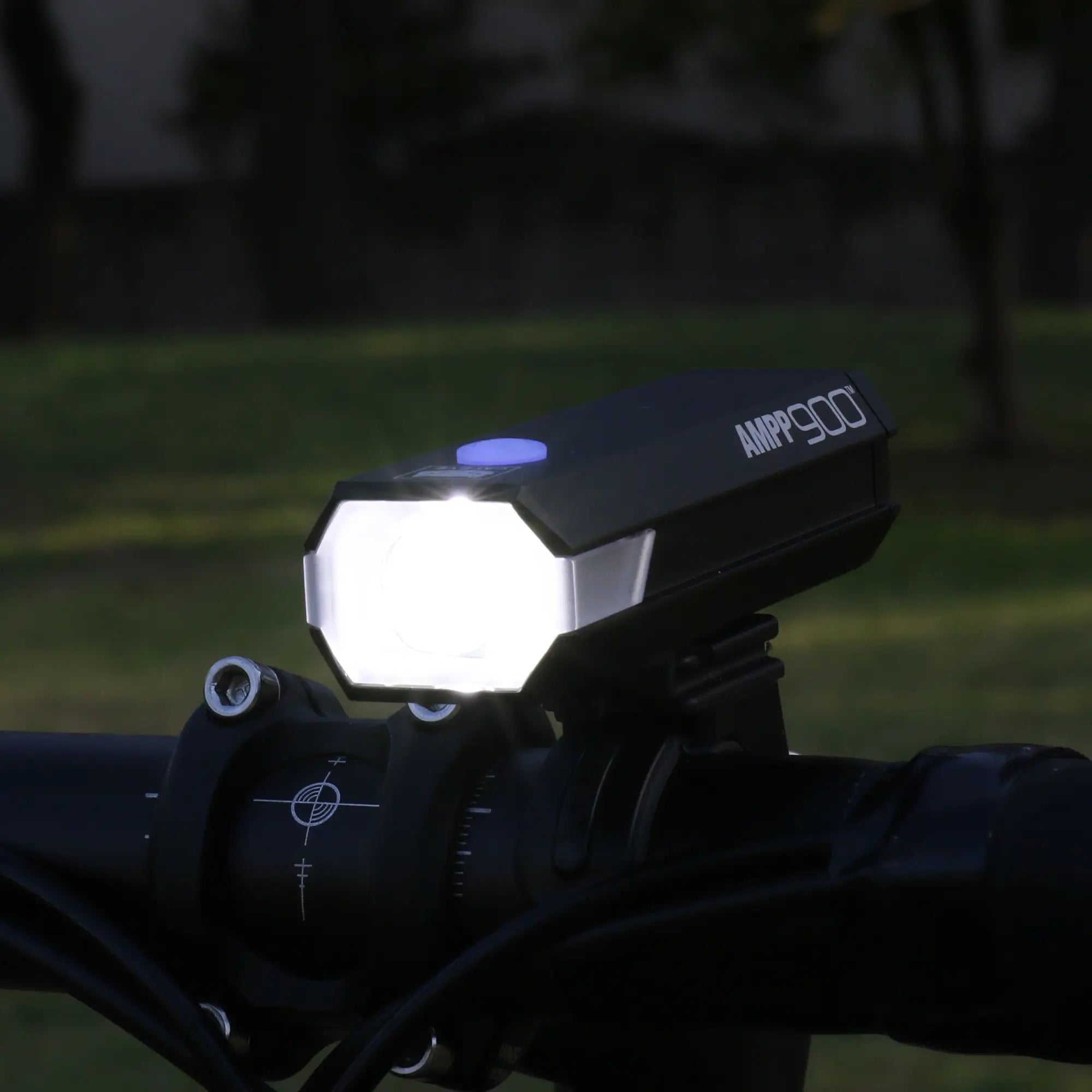 The CATEYE AMPP900 bicycle headlight is mounted on a handlebar, projecting a 900 lumen beam with OptiCube™ lens technology for bright illumination outdoors at dusk or night.