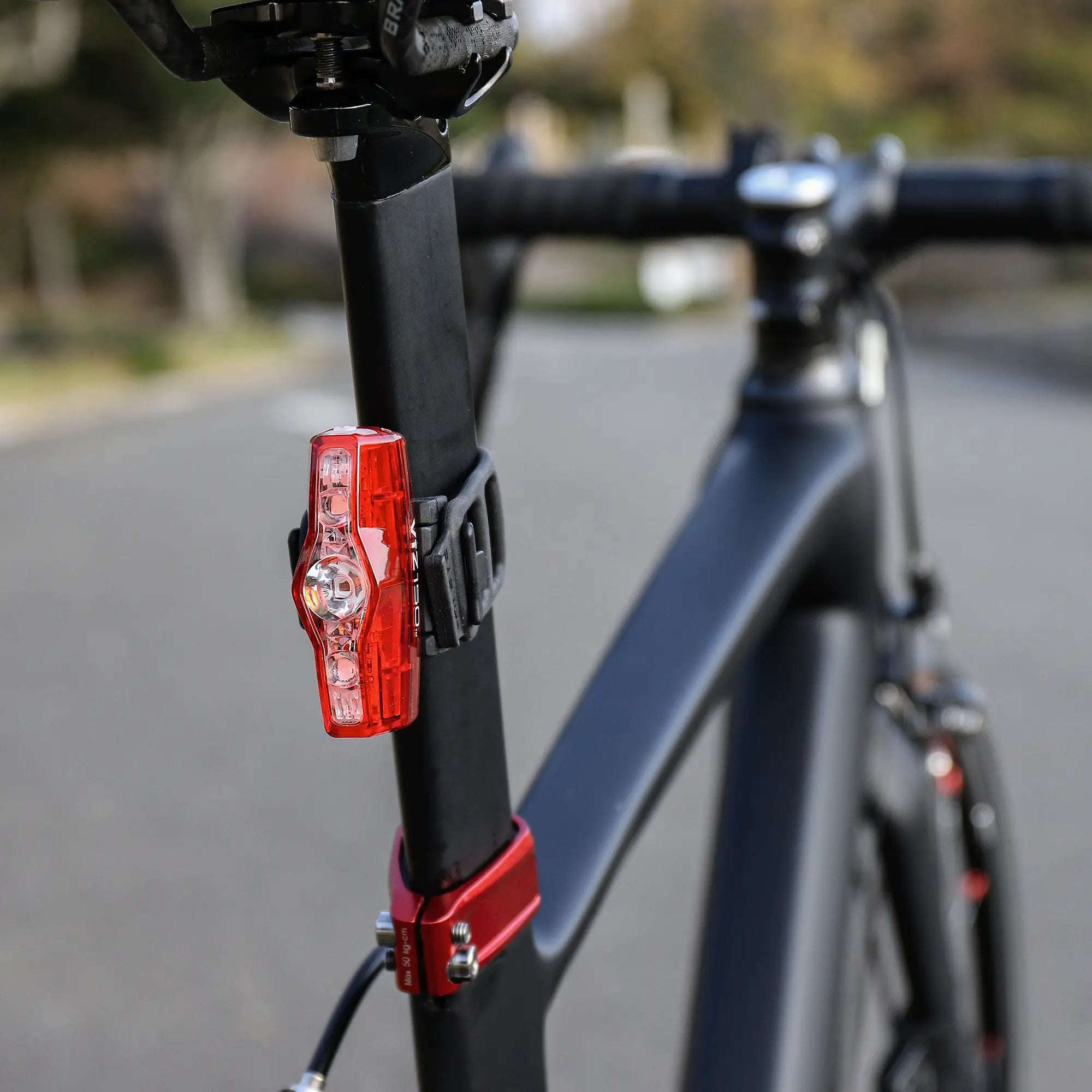 Close-up of the CATEYE ViZ150 (USB-C) LED bike light with OptiCube™ lens technology mounted on a matte black bike seat post, set against a blurred outdoor background.