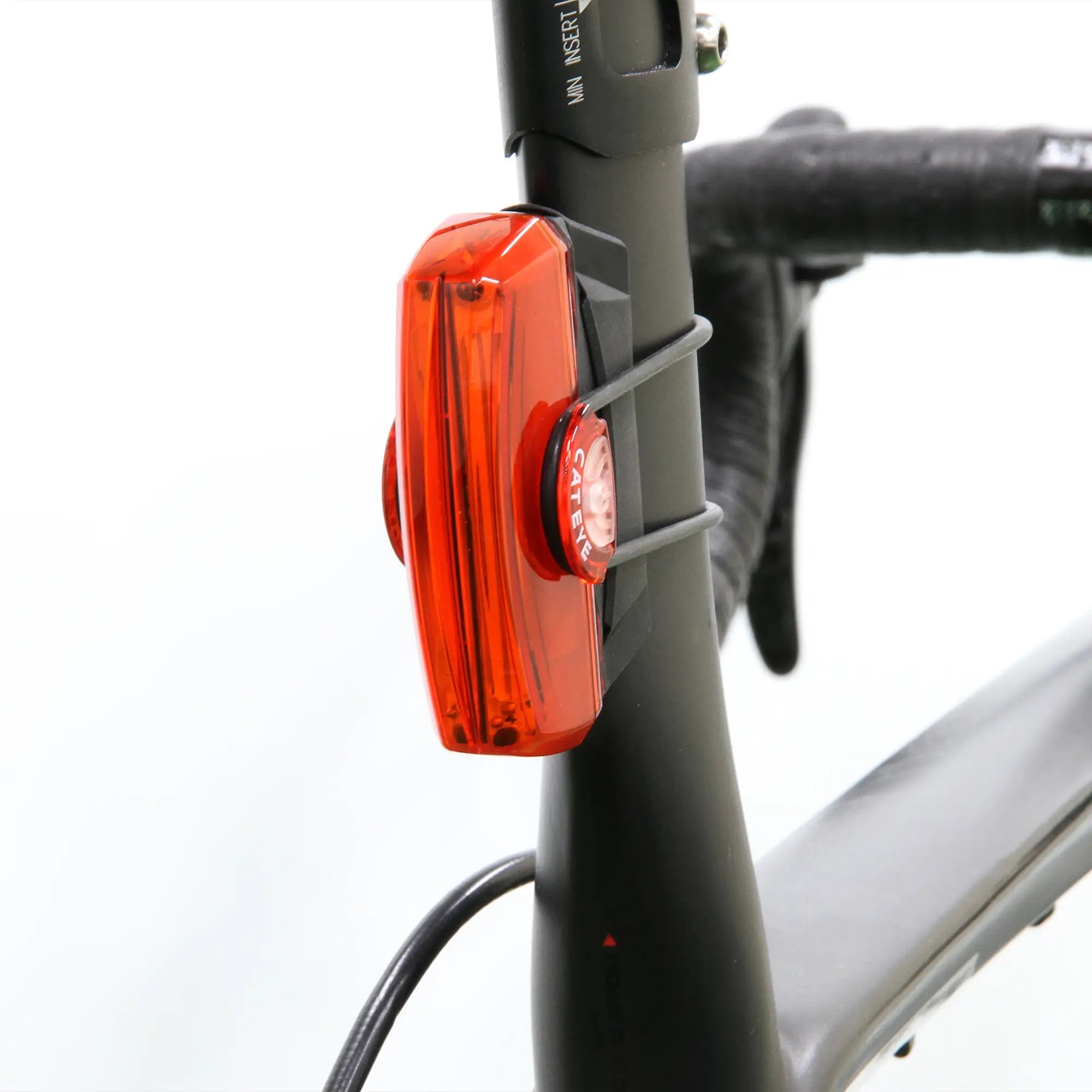 The CATEYE Sharp Aero Rubber Base for Rapid X2/X3 is securely attached to the seat post of a black bike using rubber straps, with part of the frame and handlebars visible against a plain white background.