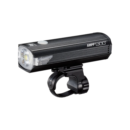 A CATEYE AMPP1300 black bicycle headlight with OptiCube lens technology and a white top button is mounted on a black handlebar bracket, displayed against a plain background.