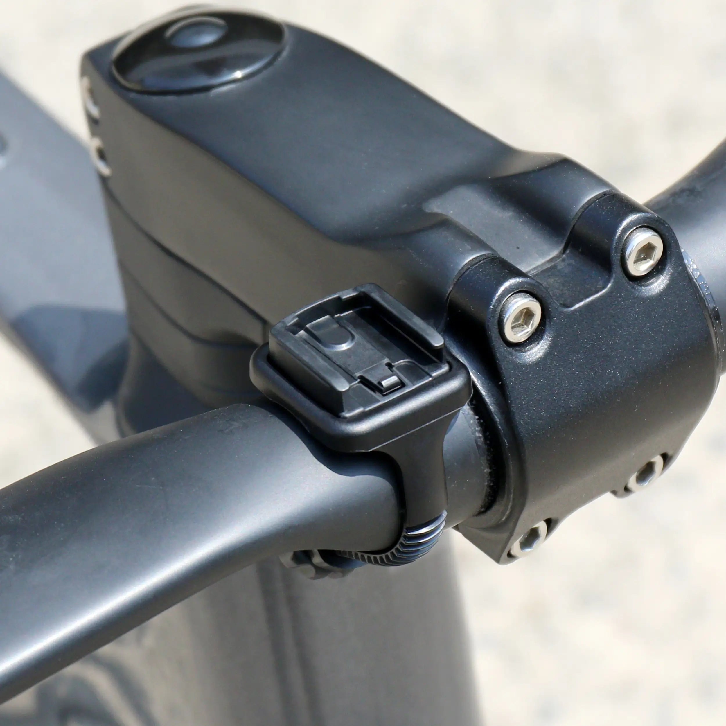 Close-up of a black bicycle handlebar with a CATEYE Flextight™ Computer Mount near the stem, highlighting detailed bolts and frame—perfect for mounting CATEYE wireless cycling computers.