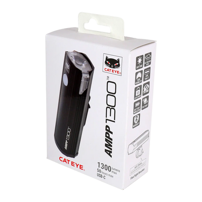 A white CATEYE AMPP1300 retail box displays the cycling headlight image, product specs, OptiCube lens info, plus icons for 1300 lumens brightness, 50-hour runtime, and USB-C charging.